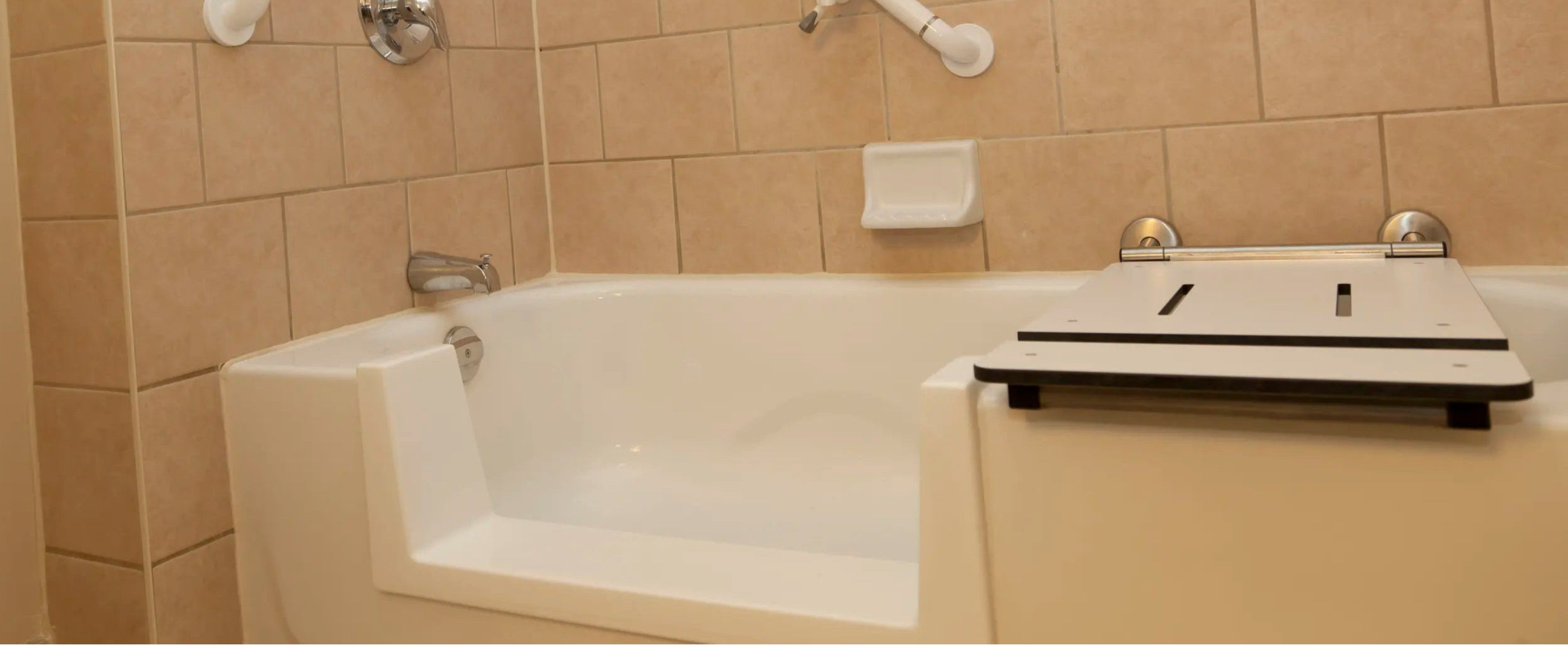 Bathroom with a bathtub, grab bars, and a shower head.